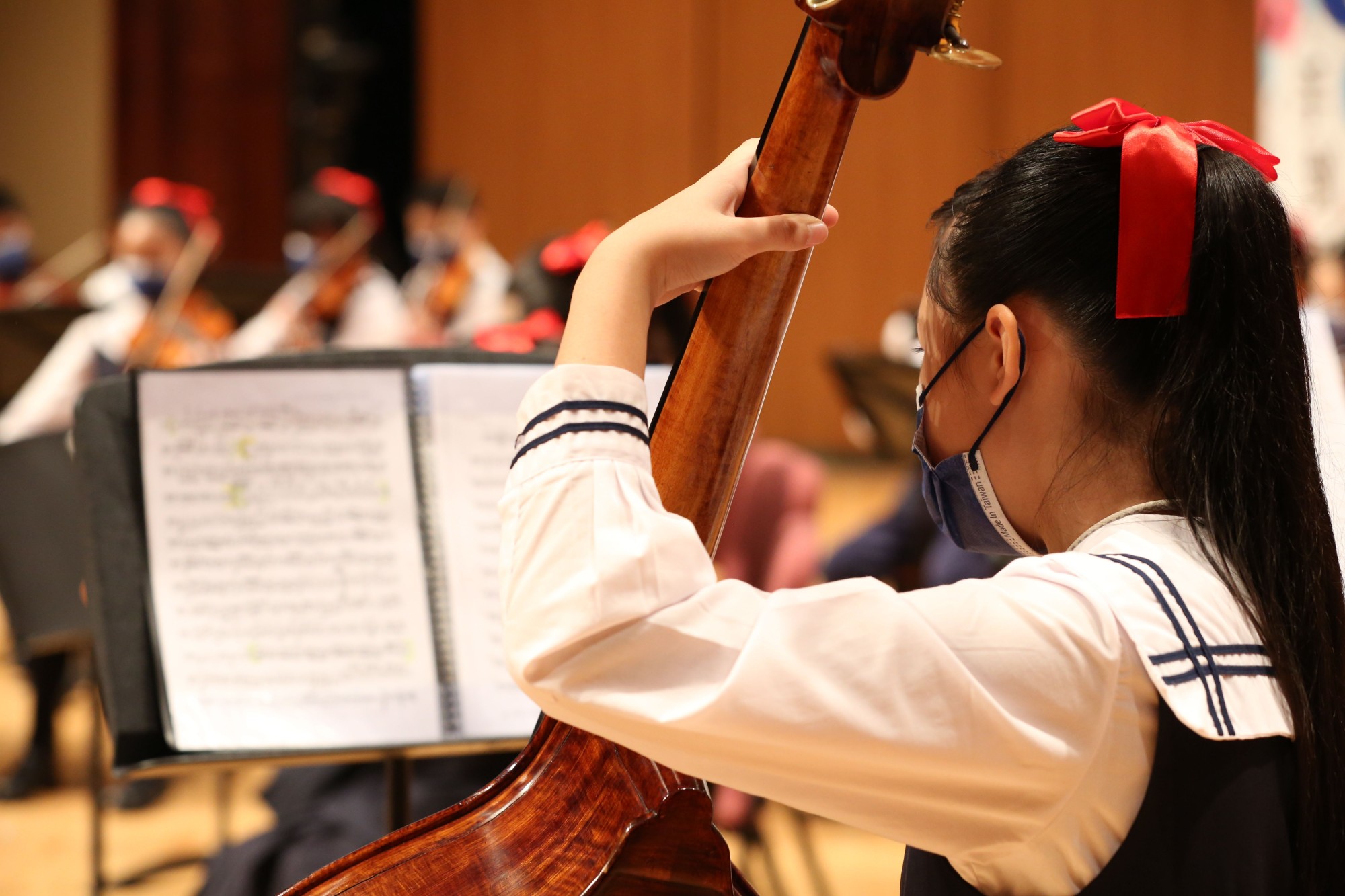 A student playing double bass in a school ensemble rehearsal